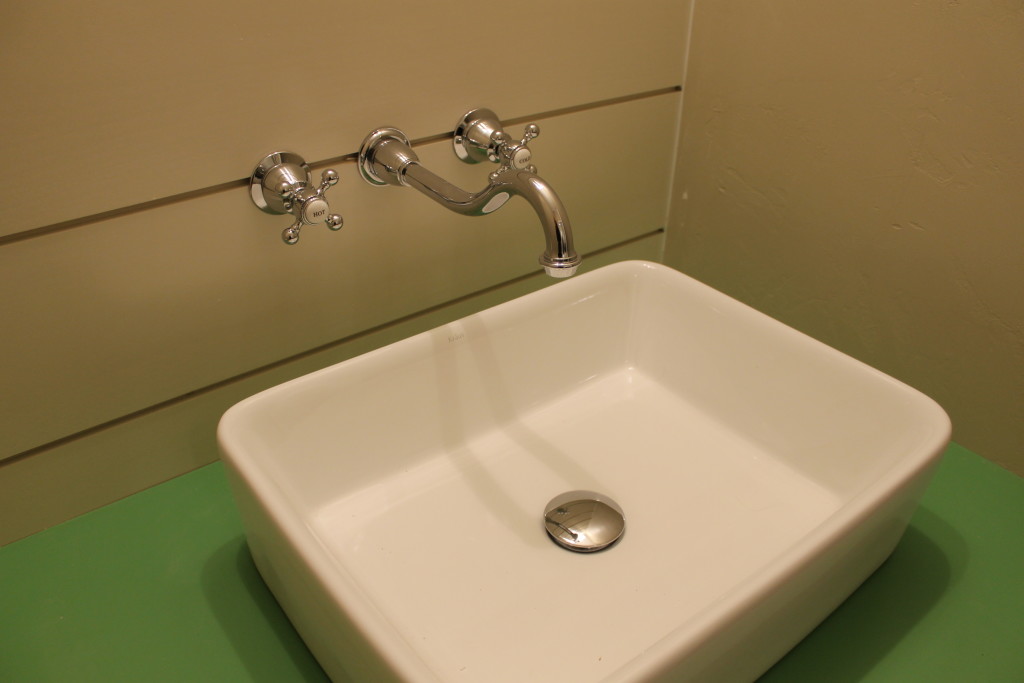 painted vanity with vessel sink and faucet in wall